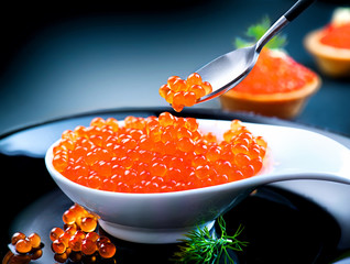Caviar. Red caviar in spoon on a black background - Powered by Adobe