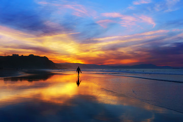 man walking on the beach at sunset - obrazy, fototapety, plakaty