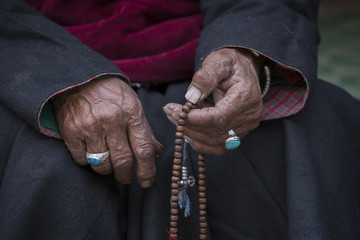 Old Tibetan woman holding buddhist rosary in Hemis monastery, Ladakh, India.