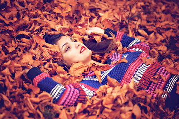 autumn woman lying over leaves and smiling, top view