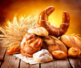 Various bread and sheaf of wheat ears on a wooden table