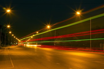 Gree, red light trails car on Night Road at suburban 
