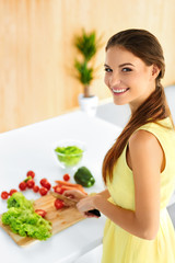 Obraz na płótnie Canvas Healthy Food. Happy Smiling Young Woman Preparing Vegetarian Dinner, Cutting Vegetables, Cooking Salad With Knife In Kitchen. Healthy Lifestyle And Eating. Diet, Dieting Concept. Nutrition