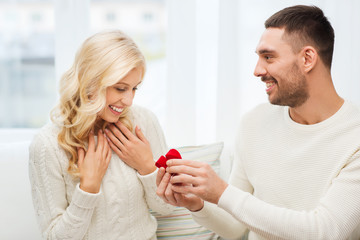 happy man giving engagement ring to woman at home