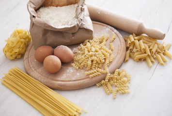 Raw homemade pasta and ingredients for pasta on wooden background