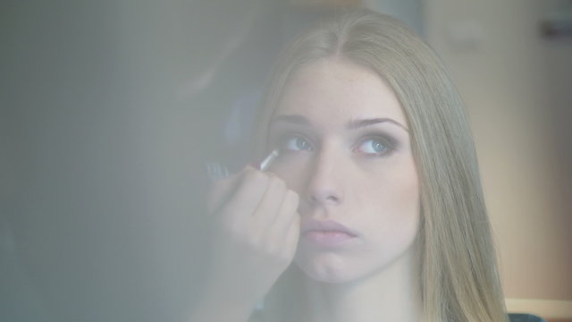 Beautiful model gets a professional makeup done by a visagist. Close-up.
