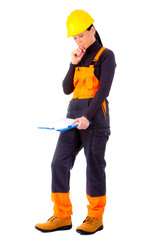 Attractive woman builder with notepad in hand, concentrate on the job, yellow helmet, orange boots and blue overalls, makes decision, positive human emotions, isolated white background.