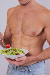 Close up of muscular man eating salad. Healthy life style, vegetarian bodybuilding concept.