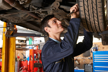 Obraz na płótnie Canvas Apprentice Mechanic Working Under Car