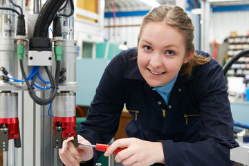 Female Apprentice Engineer Working On Machinery In Factory