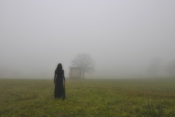 Woman with black dress, alone in the fog, Italy