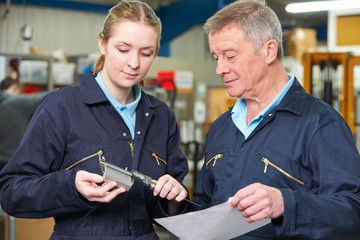 Apprentice Engineer Measuring Component With Micrometer