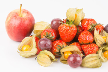 View of red apple with orange physalis, purple grapes and red strawberries on white background.