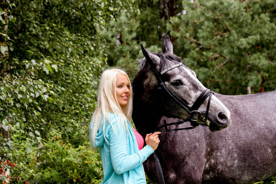 Beautiful blonde woman and her horse in rural area