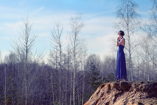Girl in a blue dress standing on the hill