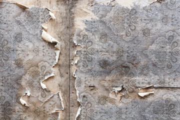 Aged room wall background with torn vintage wallpaper.