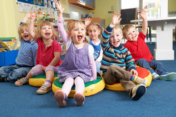 Group Of Pre School Children Answering Question In Classroom