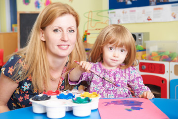 Fototapeta premium Teacher Helping Pre School Pupil In Art Class