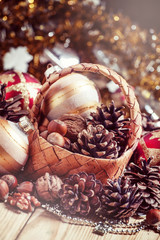 Wicker basket with fir cones, nuts, Christmas balls, tinsel and