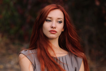Outdoors portrait of beautiful young woman with red hair