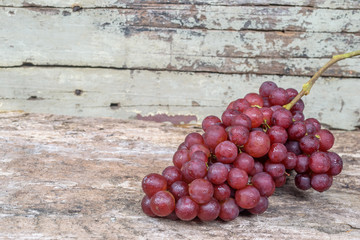 Bunch of red grapes on old wooden background.
