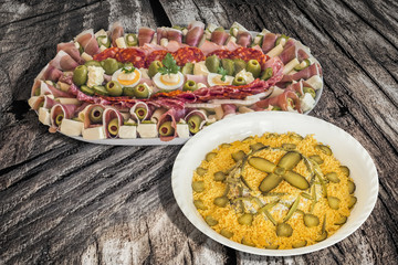 Russian Salad with Appetizer Dish Meze on Old Cracked Peeled off Wooden Garden Table. 