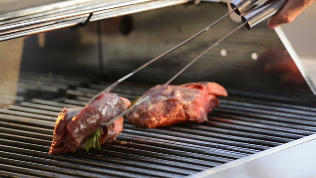 Grilling beef fillet steak on the barbecue or BBQ with olive oil and rosemary in high definition footage