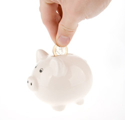 Hand putting one euro coin into piggy bank isolated on white