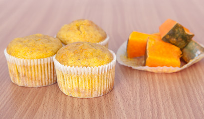 Three cupcakes and pumpkin on wood texture table
