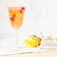 Glass of cranberry cocktail with vintage books and pearls