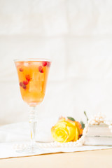 Glass of cranberry cocktail with vintage books and pearls