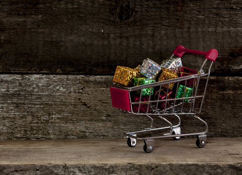 trolley cart with gift boxes over wooden background