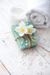 Obraz na płótnie Canvas Spa setting with jasmine blossom, natural handmade soap and sea salt on white wooden table