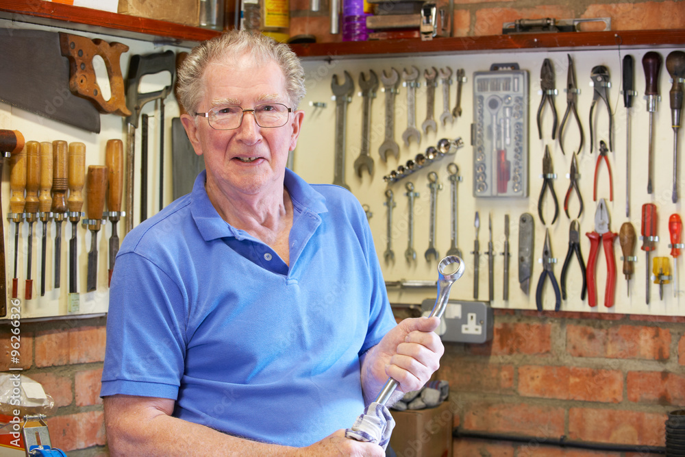 Wall mural senior man in workshop standing with tools