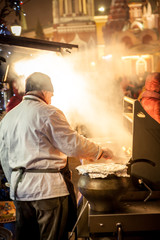 Man in front of his food cart cooking on street market in Europe city