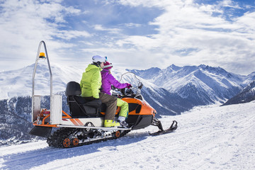 Young couple riding snowmobile snow mountain road - 96268116