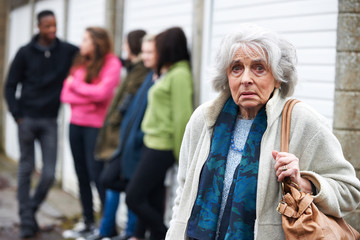 Senior Woman Feeling Intimidated By Group Of Young People