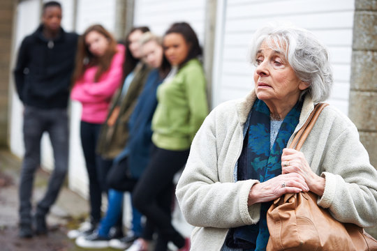 Senior Woman Feeling Intimidated By Group Of Young People