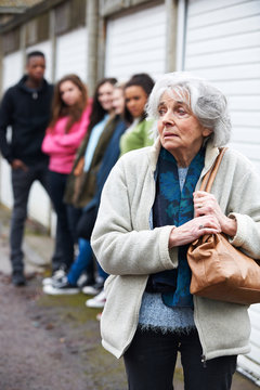 Senior Woman Feeling Intimidated By Group Of Young People