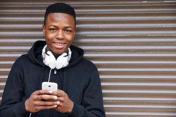 Teenage Boy Listening To Music And Using Phone In Urban Setting - Powered by Adobe