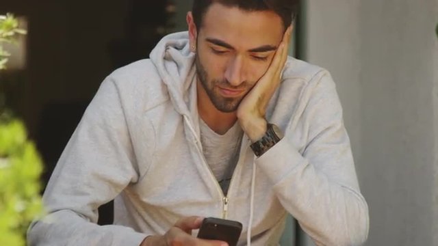 Cute hispanic man using smartphone outdoors