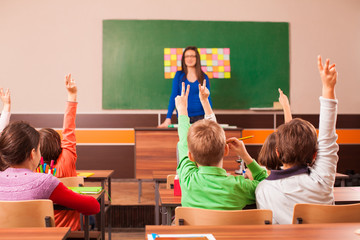 Children in elementary school are raised hand in clasroom
