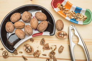 Walnut dessert preparation. Whole and chopped walnuts in multicolored dishes and nutcracker on...