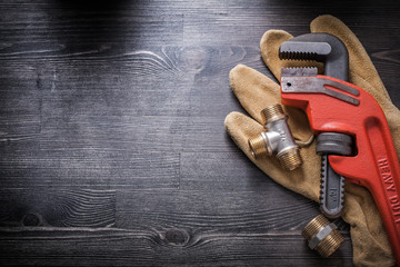 Pipe wrench plumbing fixtures protective gloves on wooden board