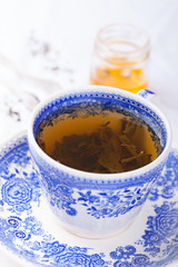 Green tea in a blue cup with honey on a background. Closeup.
