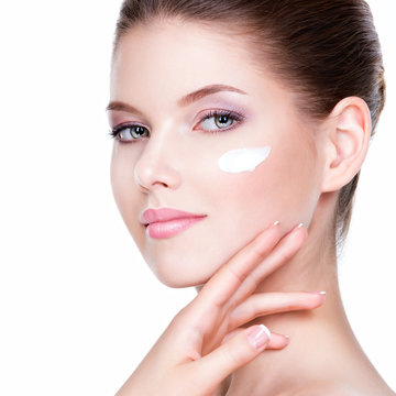 Beauty face of young woman with cosmetic cream on a cheek.
