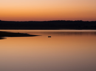 Man on boat at sunset in a lake
