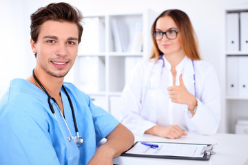 Fototapeta premium Attractive male doctor near female doctor