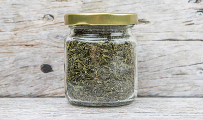 Dried Japanese green tea leaves in mason jar over wooden background