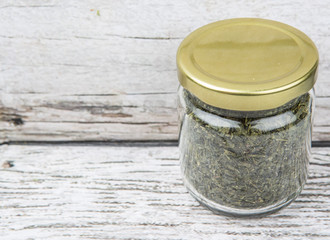 Dried Japanese green tea leaves in mason jar over wooden background